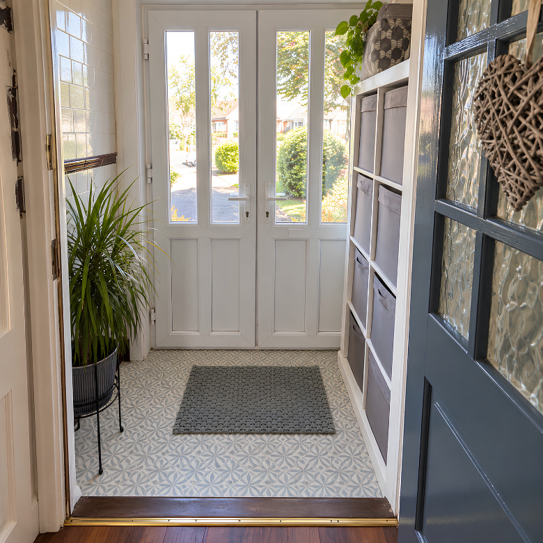 Small front porch with patterned floor tiles, white glazed doors, built-in storage and potted greenery
