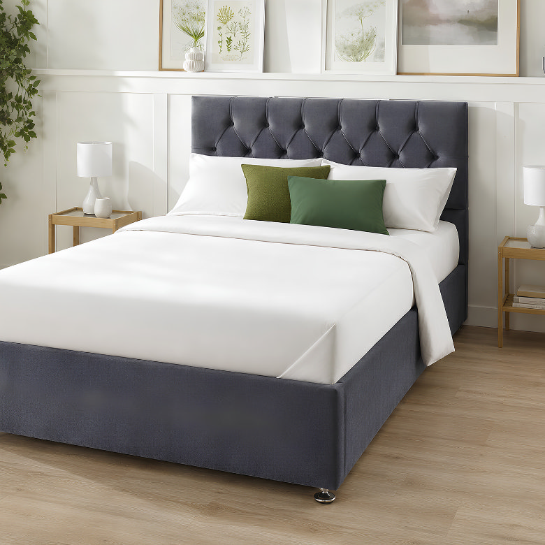 Crisp white hotel style bedding with neatly tucked hospital corners and green accent cushions on a navy upholstered bed.