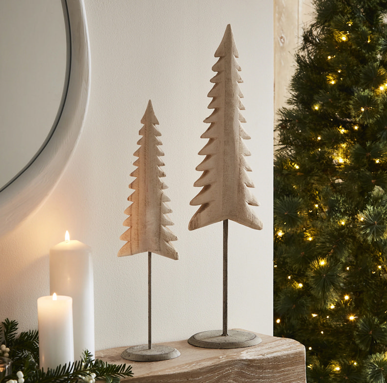two wooden tree ornaments on a fireplace
