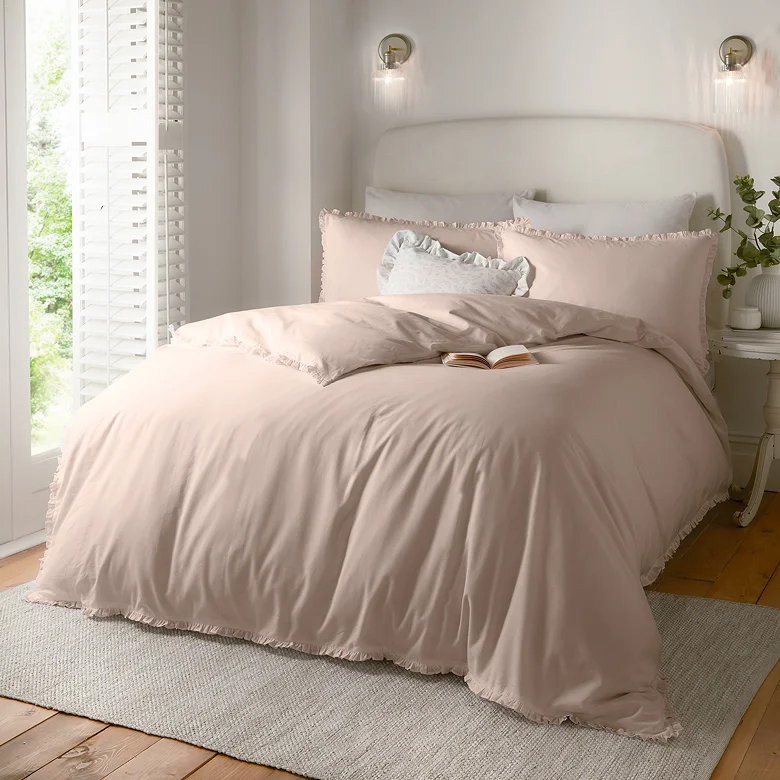 soft blush pink ruffle duvet cover set styled in light neutral bedroom with layered cushions and cosy textures