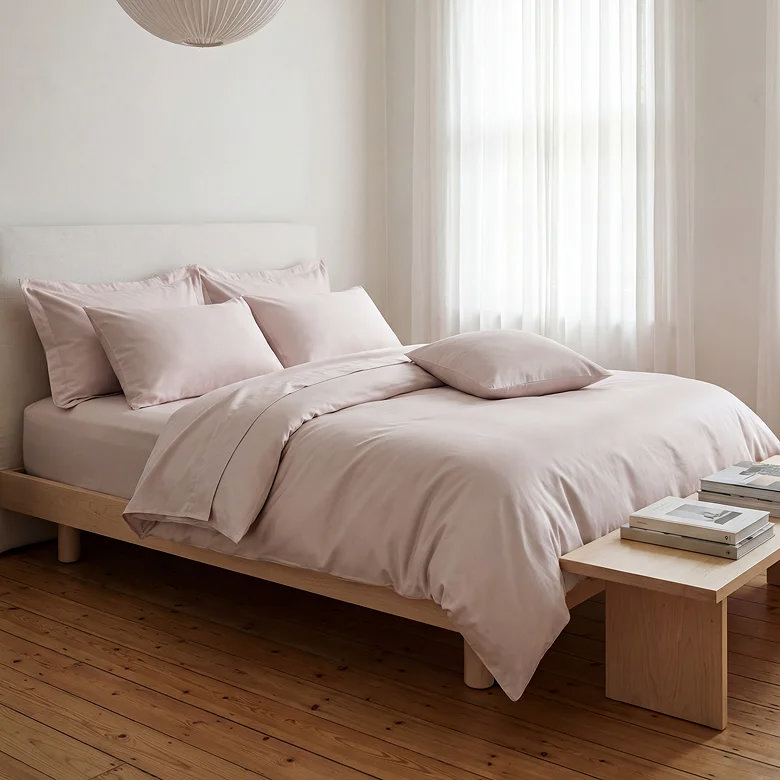 blush pink bedding set with plain duvet cover and pillowcases styled in minimal neutral bedroom with wooden furniture