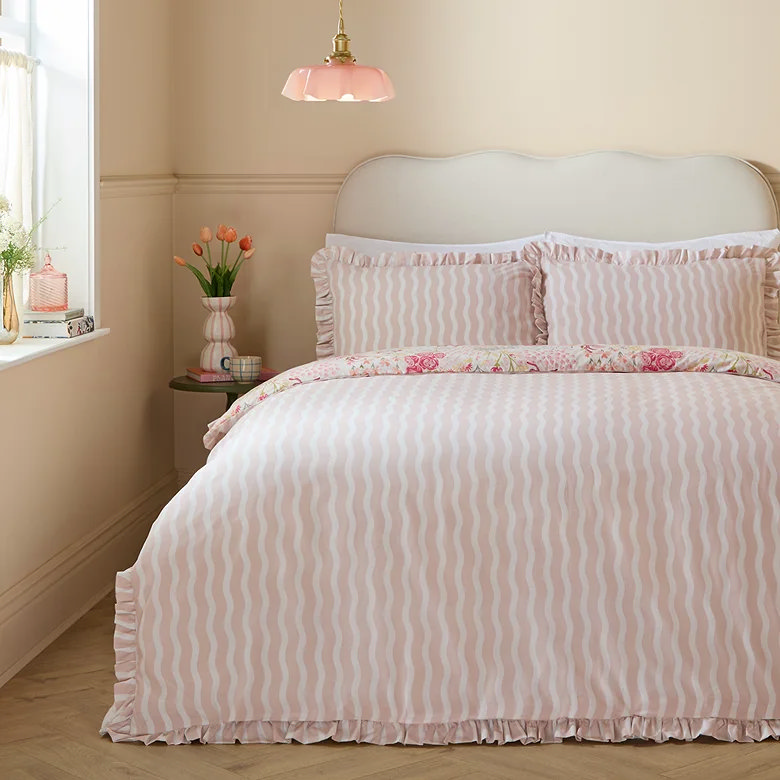 pink wavy stripe duvet cover set with ruffle trim styled on cream scalloped headboard bed