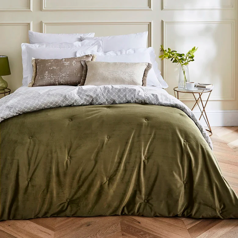 olive green velvet bedspread with button tufted finish and layered neutral bedding