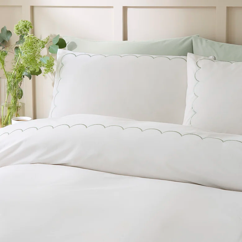 white duvet cover set with green scalloped edge trim in soft neutral bedroom