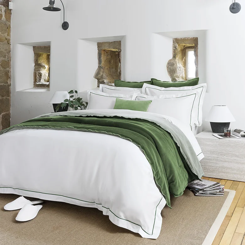 luxury white sateen duvet cover with green trim and layered sage and olive bedding