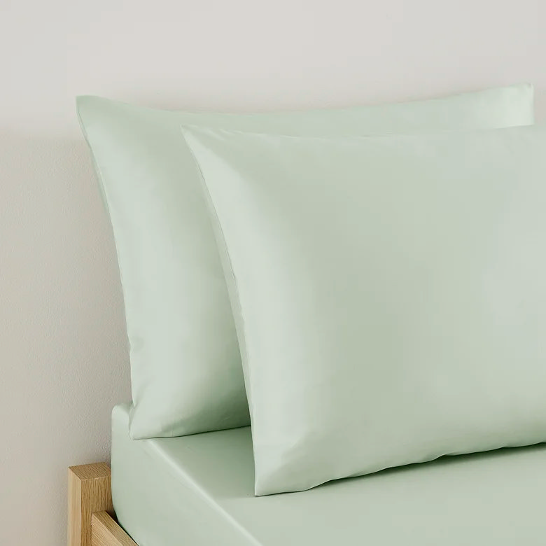 sage green pillowcases with fitted sheet set on minimalist wooden bed