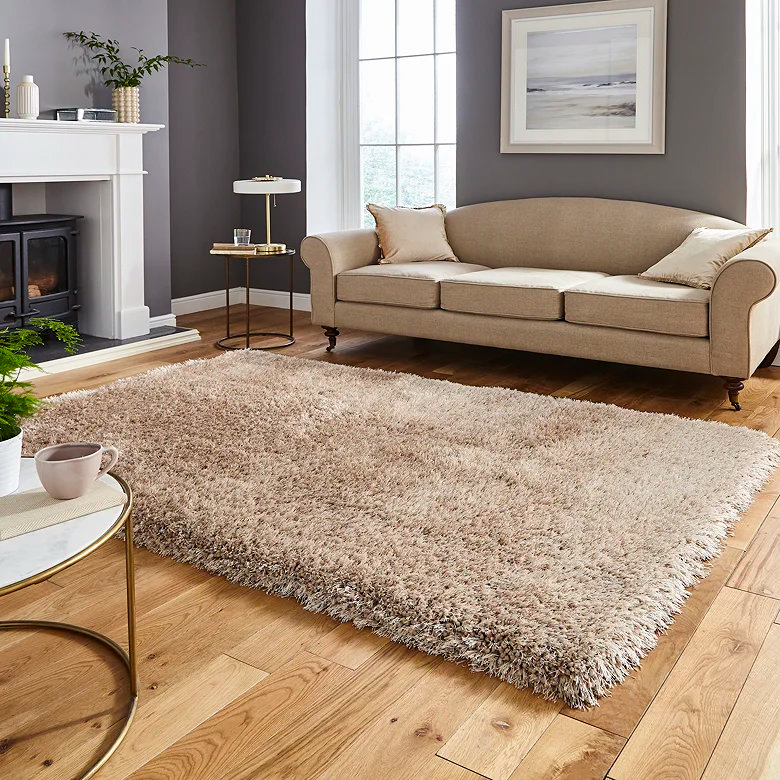 Warm beige shaggy rug beside a sofa in a cosy living room, showing a thick high-pile texture that adds softness, warmth and comfort underfoot for a home office on wooden flooring