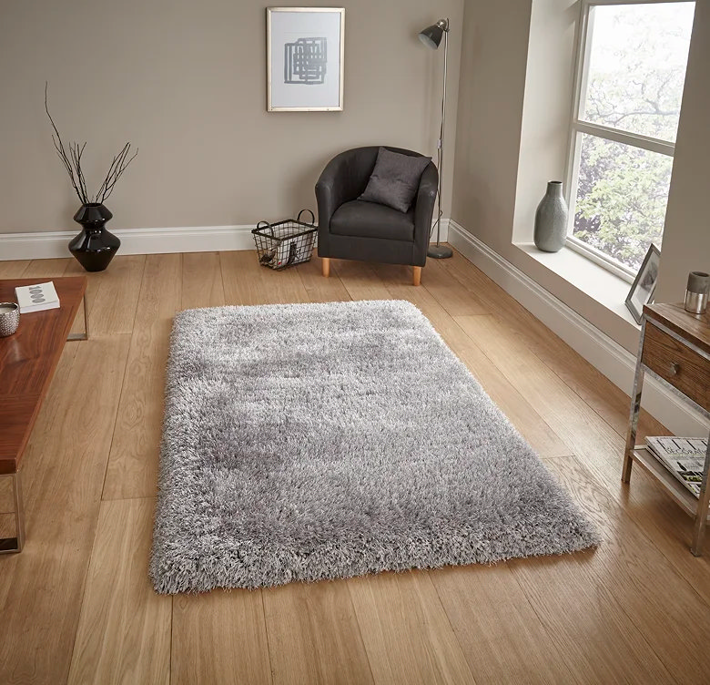 Soft silver grey shaggy rug on wooden floor next to armchair and coffee table, showing a calm, modern home office reading corner setup