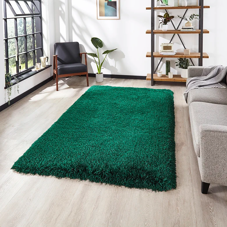 Emerald green shaggy rug on a wood floor beside a window and grey sofa, showing how choosing a rug in your favourite colour can personalise a home office or WFH nook with warmth and comfort