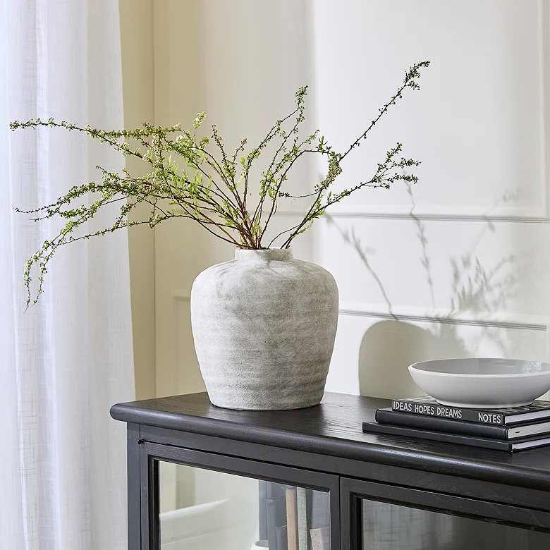 white vase with faux plant on display cabinet