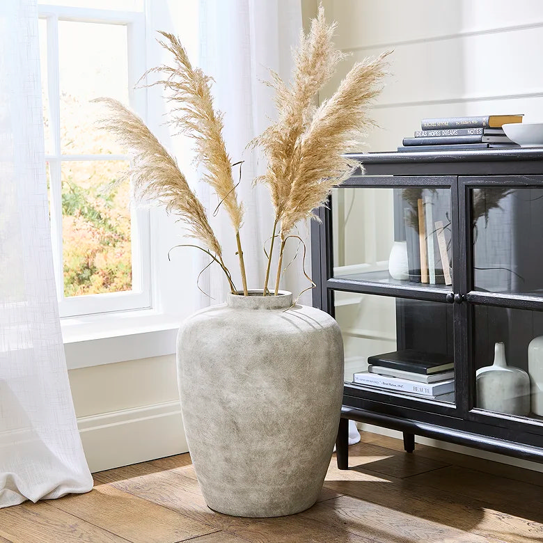 large white urn by black glassfronted display cabinet