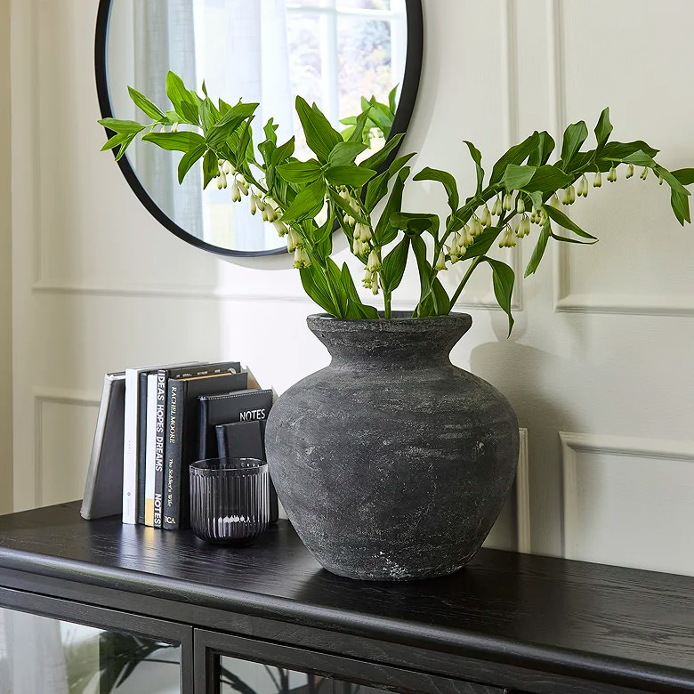 black vase and books on top of cabinet