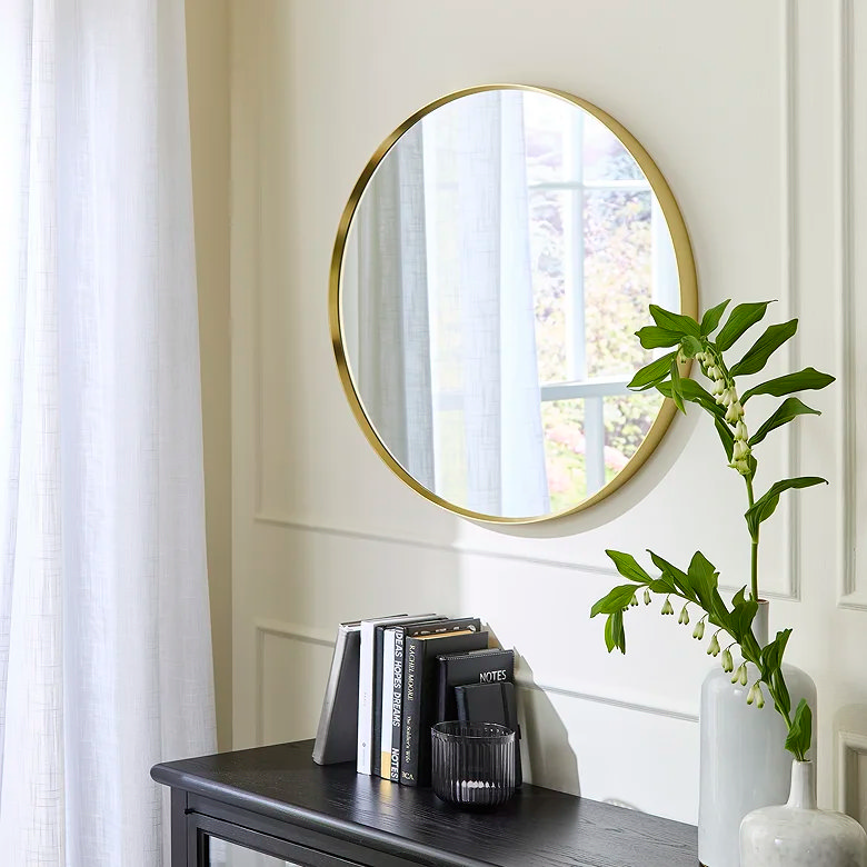 round metallic gold hallway mirror above sideboard