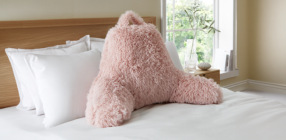 pink fluffy cuddle cushion on bed