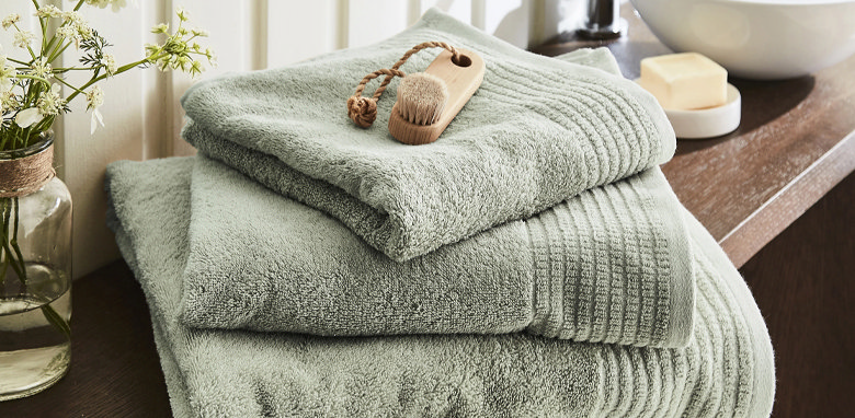 green folded bathroom towels with brush on top