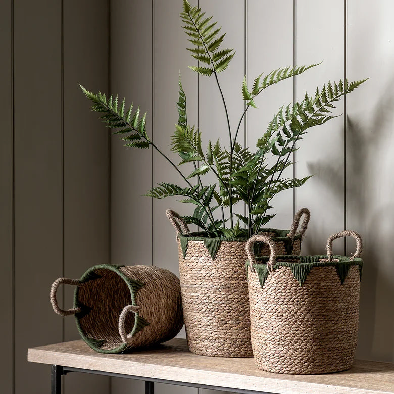three round woven baskets with green embellishments