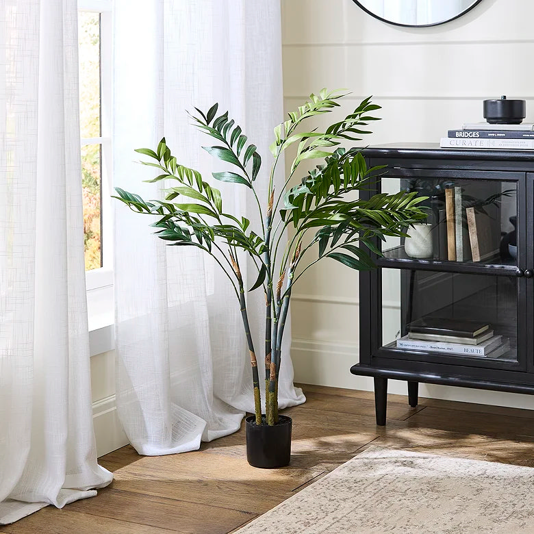 large leafy palm tree faux plant in bedroom