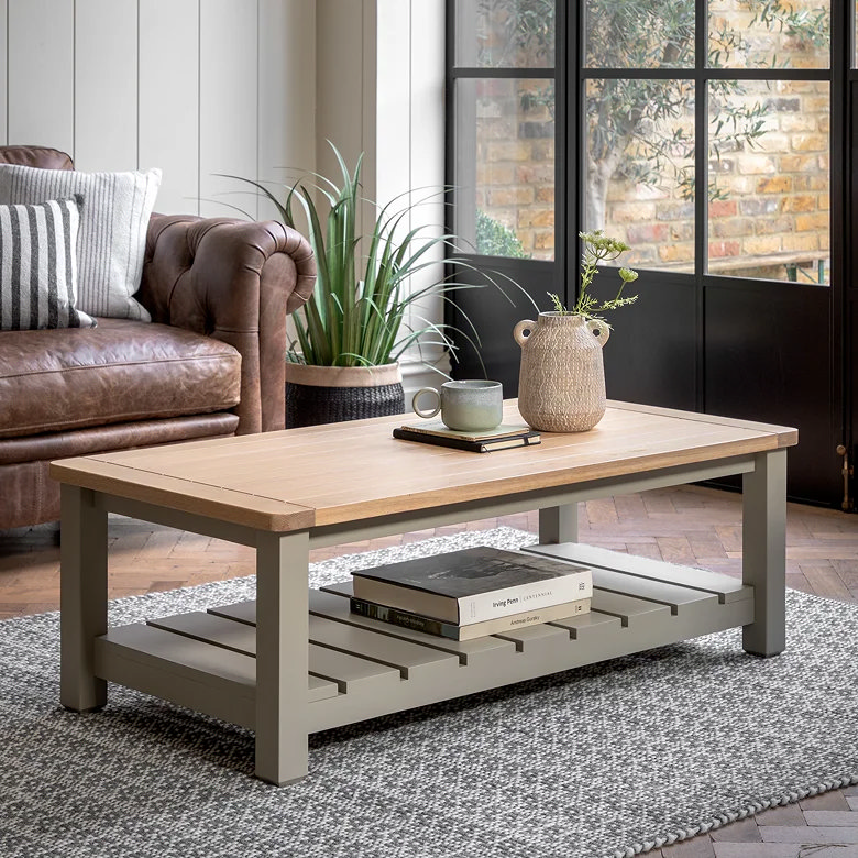 Wooden coffee table with lower shelf used for book storage in a small living room