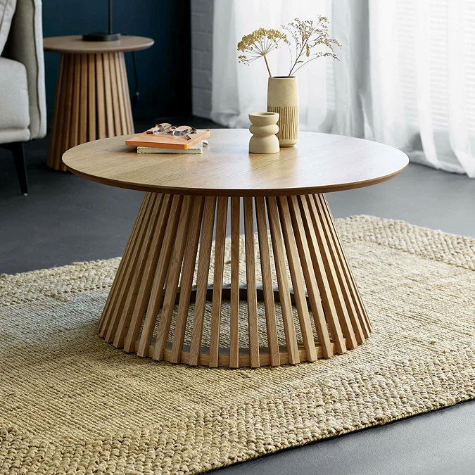 Round wooden coffee table styled simply with ceramic vases and books for a Scandi-inspired living room
