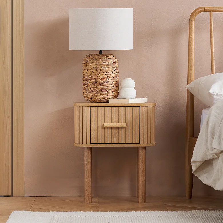 bedroom with light oak slatted bedside table and woven base lamp