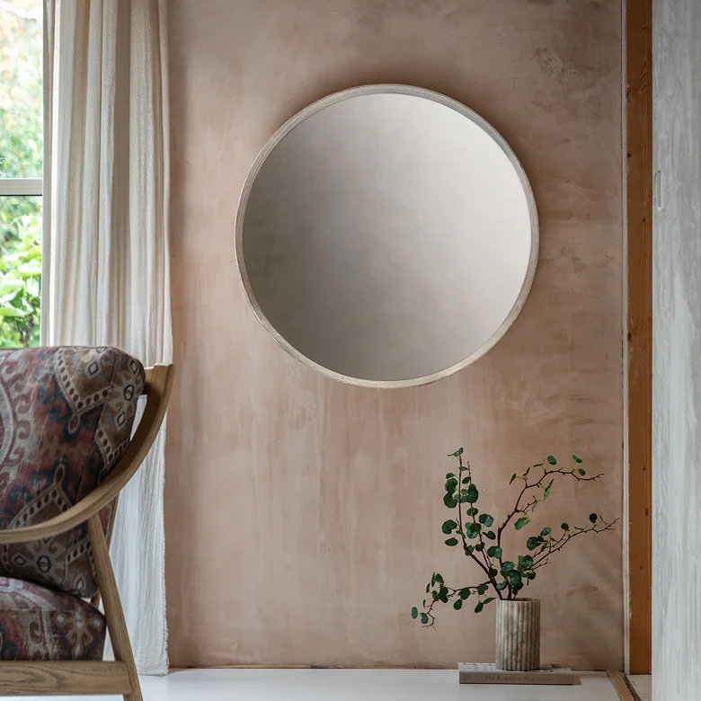 minimal dining room with round wall mirror above side surface and neutral styling