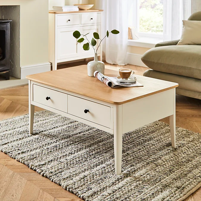 White coffee table with wooden top styled with a small vase, magazine and coffee cup in a cosy living room