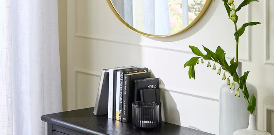 Chest of drawers styled with books, vase and mirror showing small space book storage