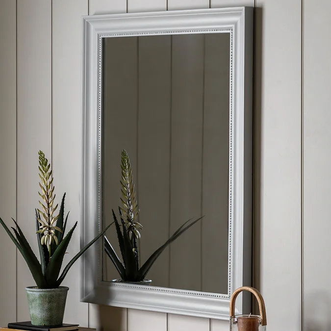Classic rectangular wall mirror with white wooden frame, styled in a modern living room to reflect light and create space.