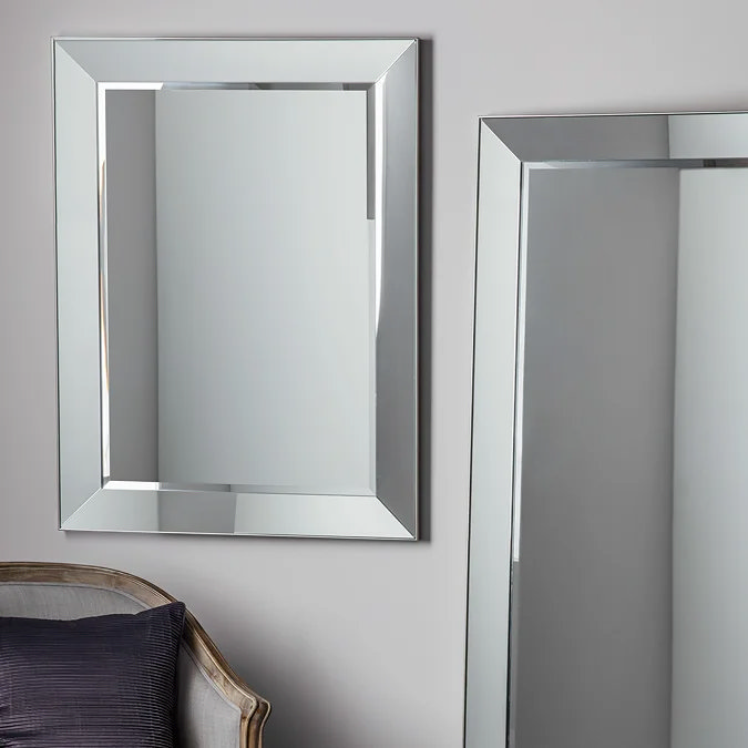 Contemporary rectangular wall mirror with angled silver frame, adding light and modern glamour to a living room wall.