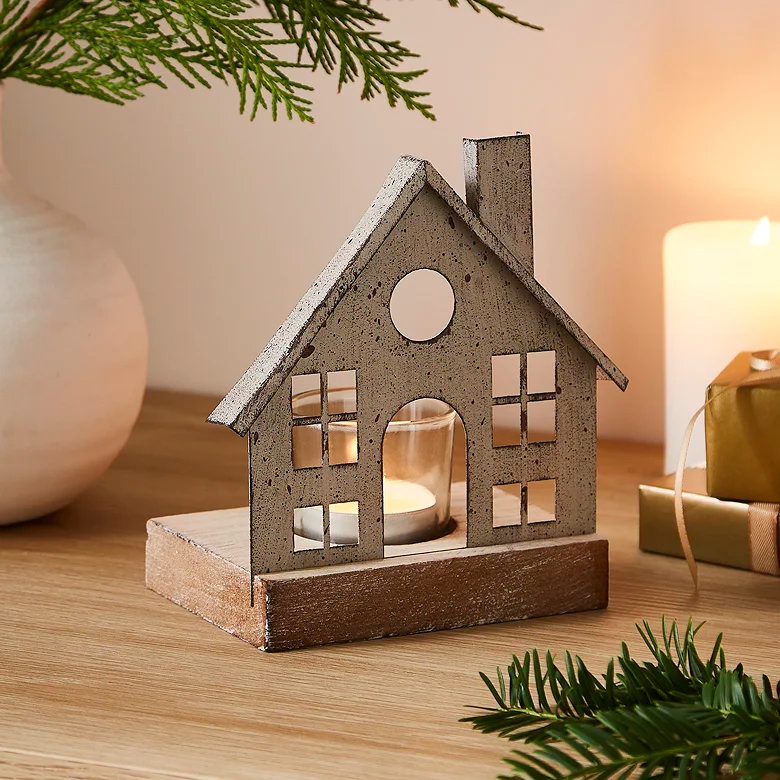 House shaped metal tealight candle holder on wooden table