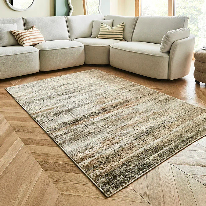 Earthy brown and beige striped rug on herringbone wood floor, showing how a warm brown office rug can ground a workspace and add cosy depth to a neutral home office or study