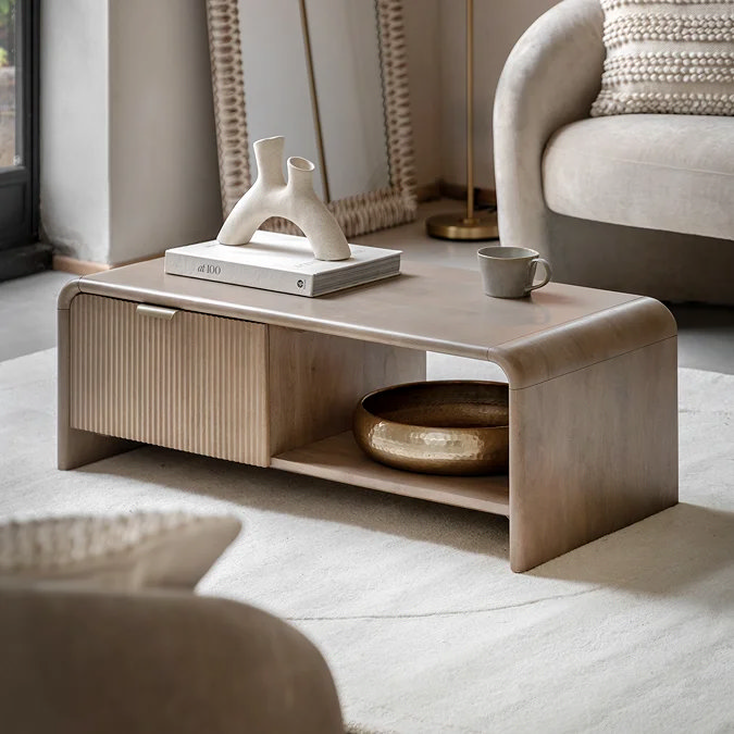 Modern wooden coffee table styled with stacked books, sculptural vase and ceramic bowl in a neutral living room