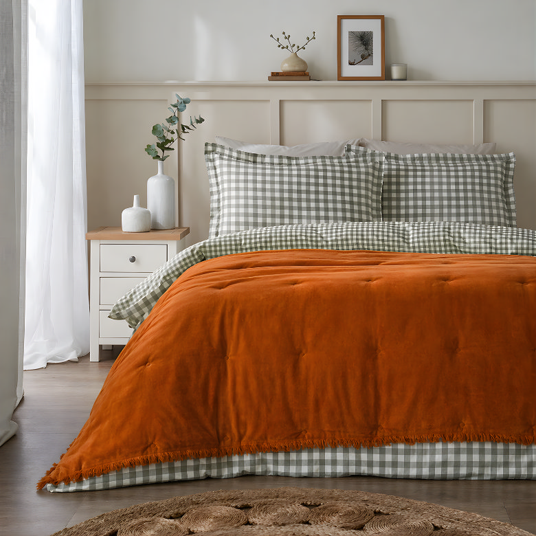 earthy bedroom with green gingham bedding and rust velvet bedspread layered on neutral bed