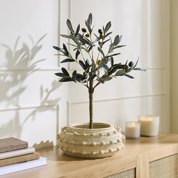 Small faux olive tree in a textured cream planter on an oak console, styled with candles for hallway greenery.