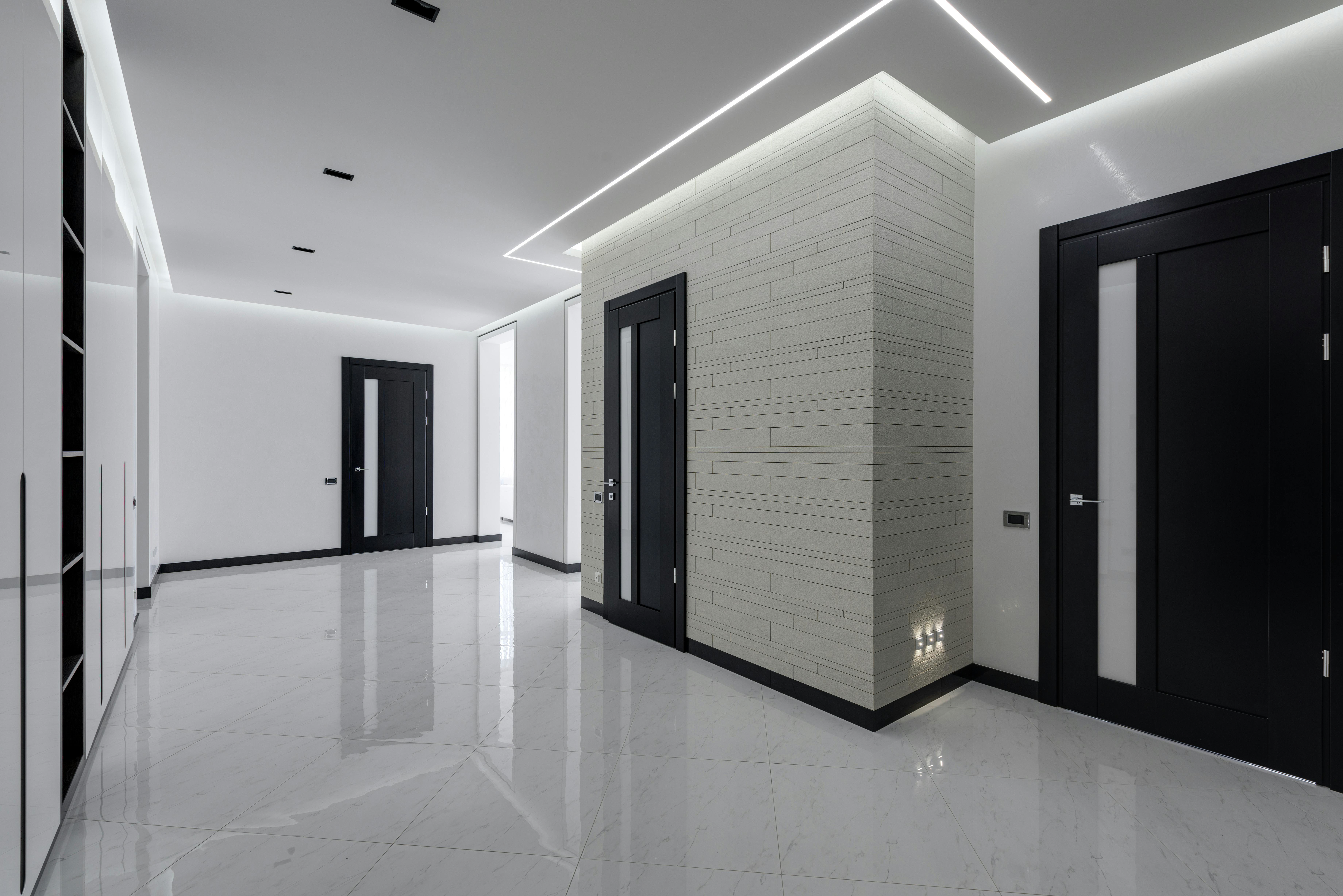 Modern hallway with concealed LED wall-wash strips and cove lighting stretching the space—layered light makes a narrow hall look wider.