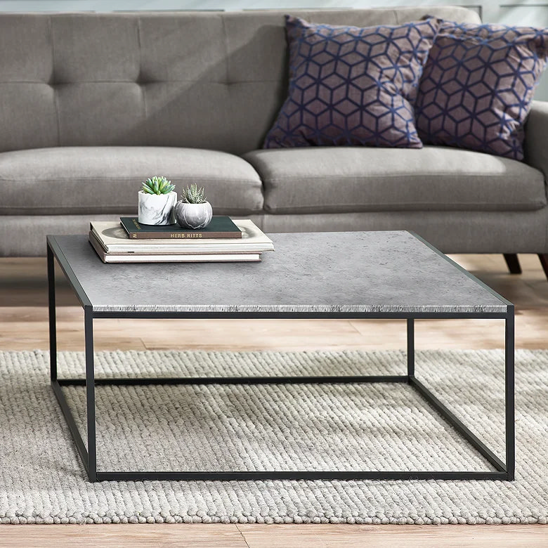 Modern coffee table with stacked books and small plants used as stylish book storage idea for small living rooms.