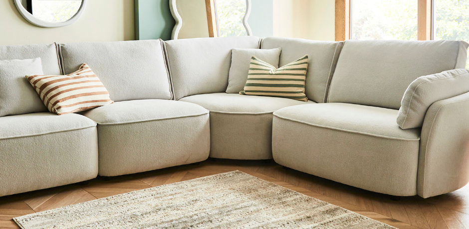 Neutral corner sofa styled with three earth tone striped sofa cushions, demonstrating balanced odd number cushion arrangement for corner sofas.