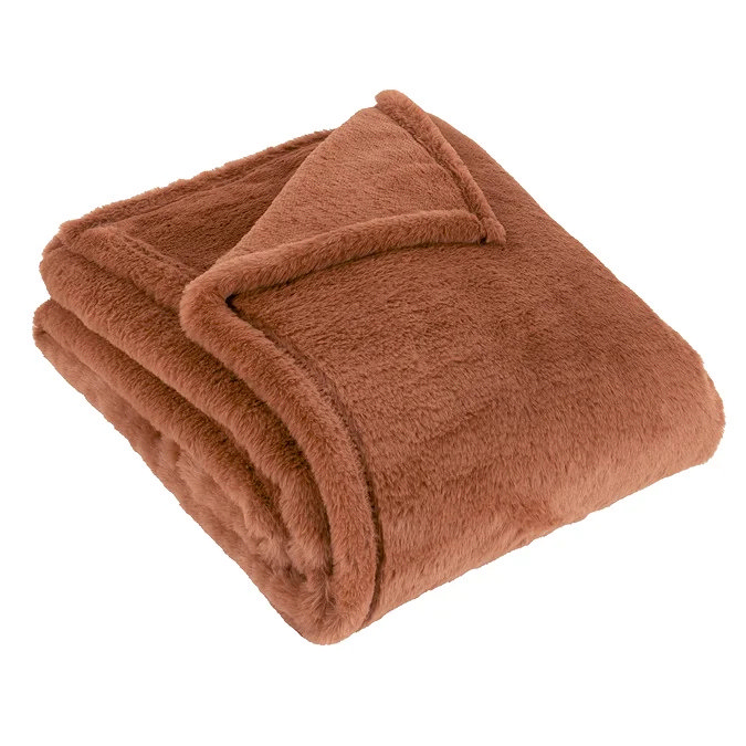 Folded faux fur throw in warm brown shade for adding texture and cosiness to a bedroom