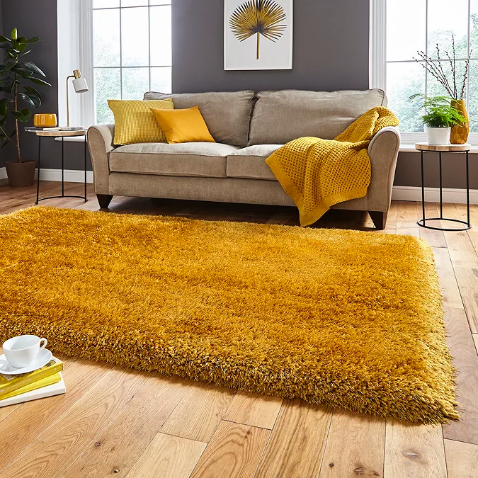 Butter yellow rug warming a neutral living room with sofa and cushions.