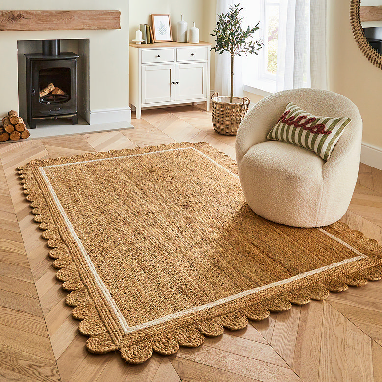 natural jute rug with scalloped edge in earthy living room with boucle chair and warm wood tones