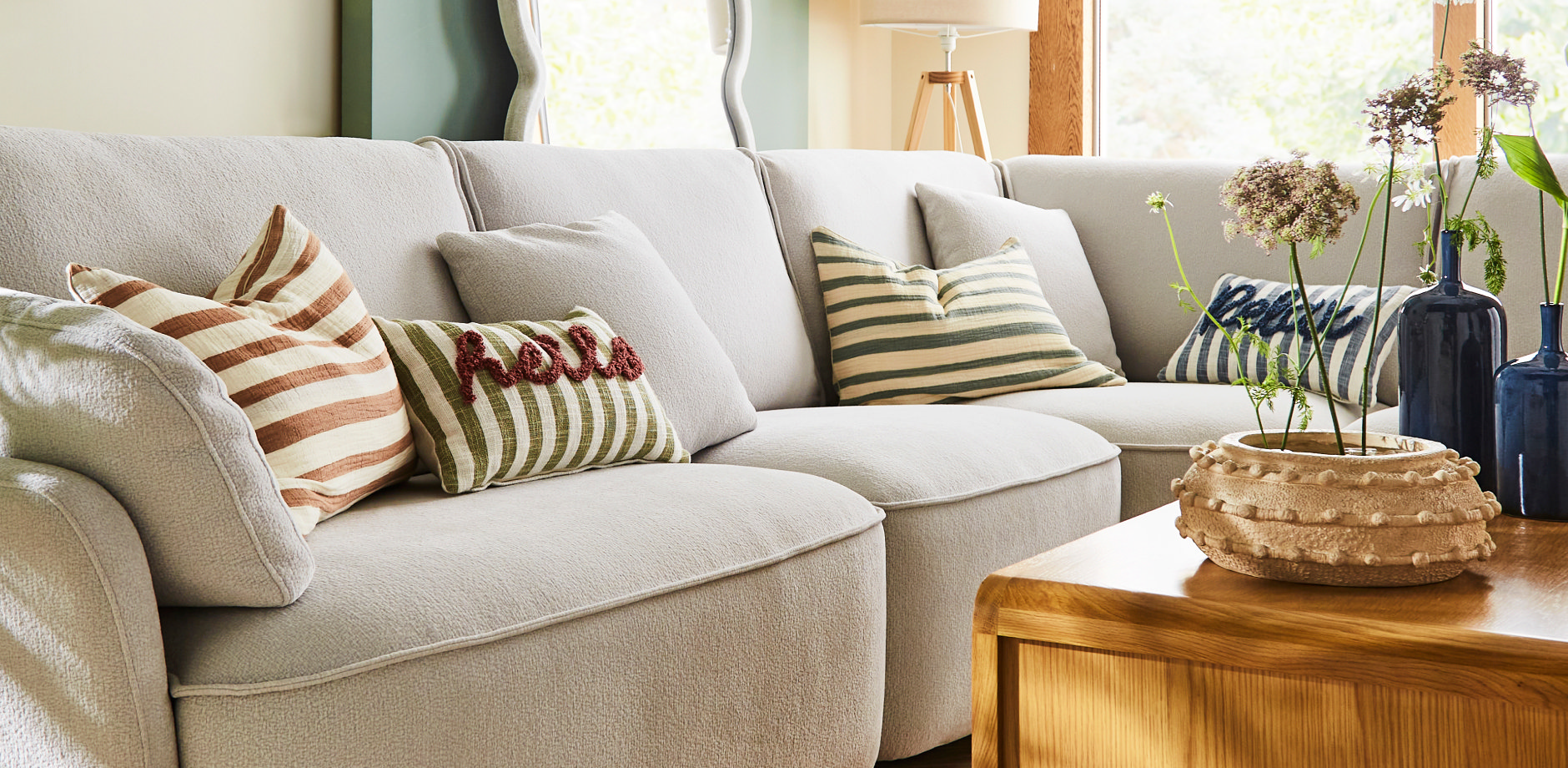 Modern living room with a grey fabric sofa styled with layered cushions in neutral and accent colours.