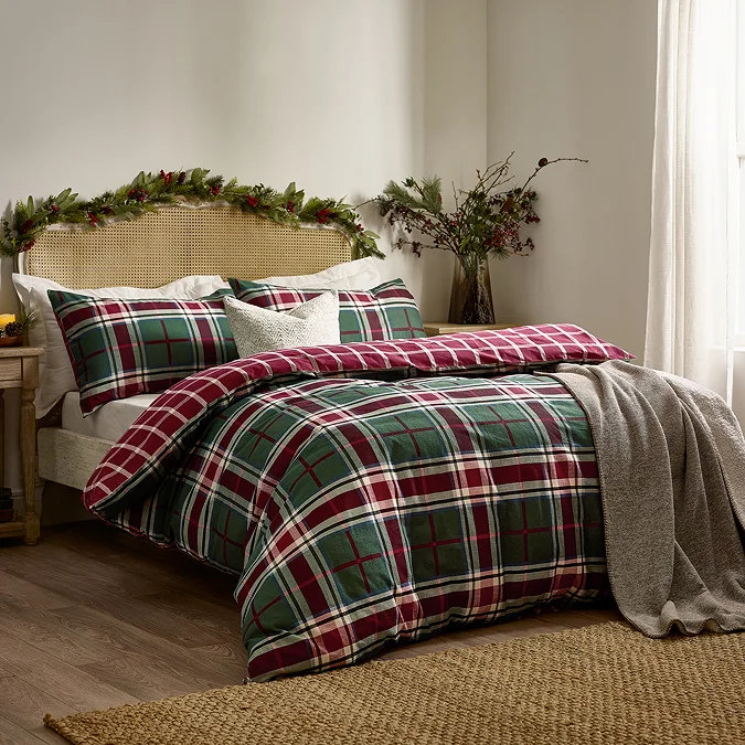 Festive bedroom with green and red checked Christmas bedding, grey throw and garland headboard