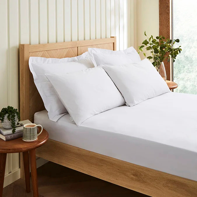 White pillows and fitted sheet on oak bed