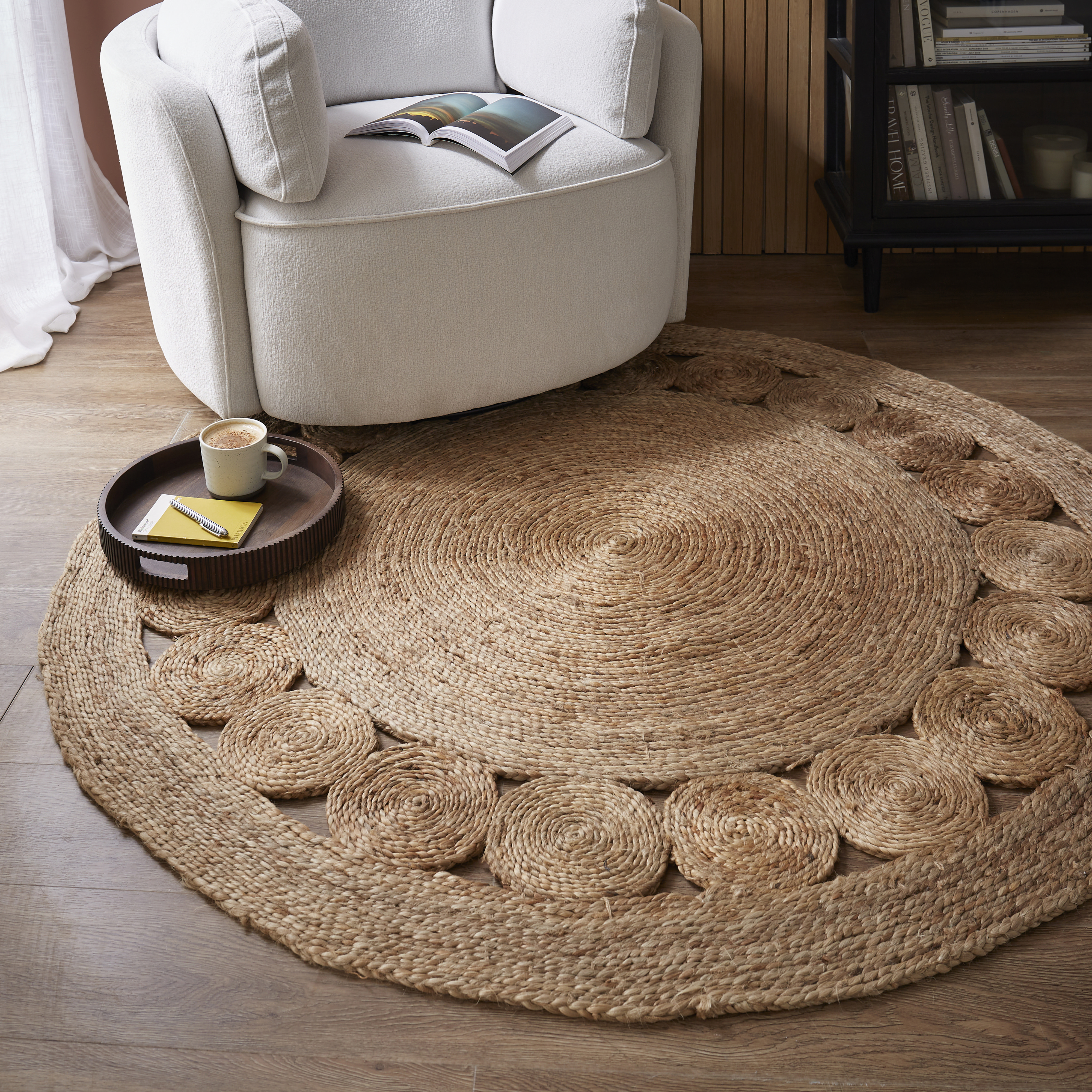 Cosy accent chair with open book and round jute rug styled with a tray for coffee and reading