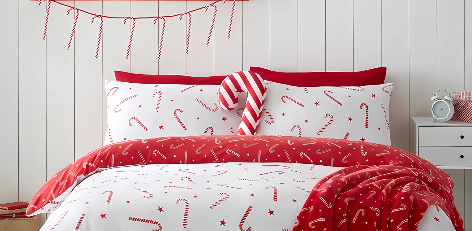 Festive bedroom with candy cane print bedding, red Christmas throw and star decoration on shelf