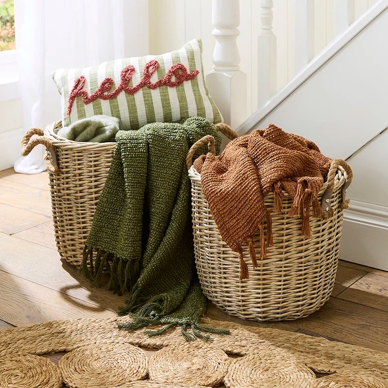 Woven storage baskets filled with throws and cushions beside staircase