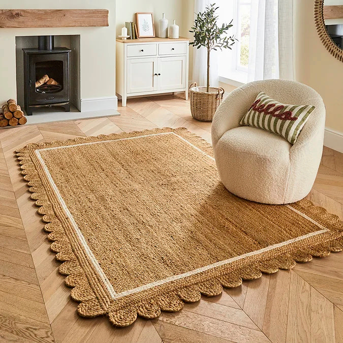 Natural scallop-edge jute rug with a wavy border in a light, modern living space, showing how an organic shape and warm neutral tone can soften hard lines and define a stylish home office zone.