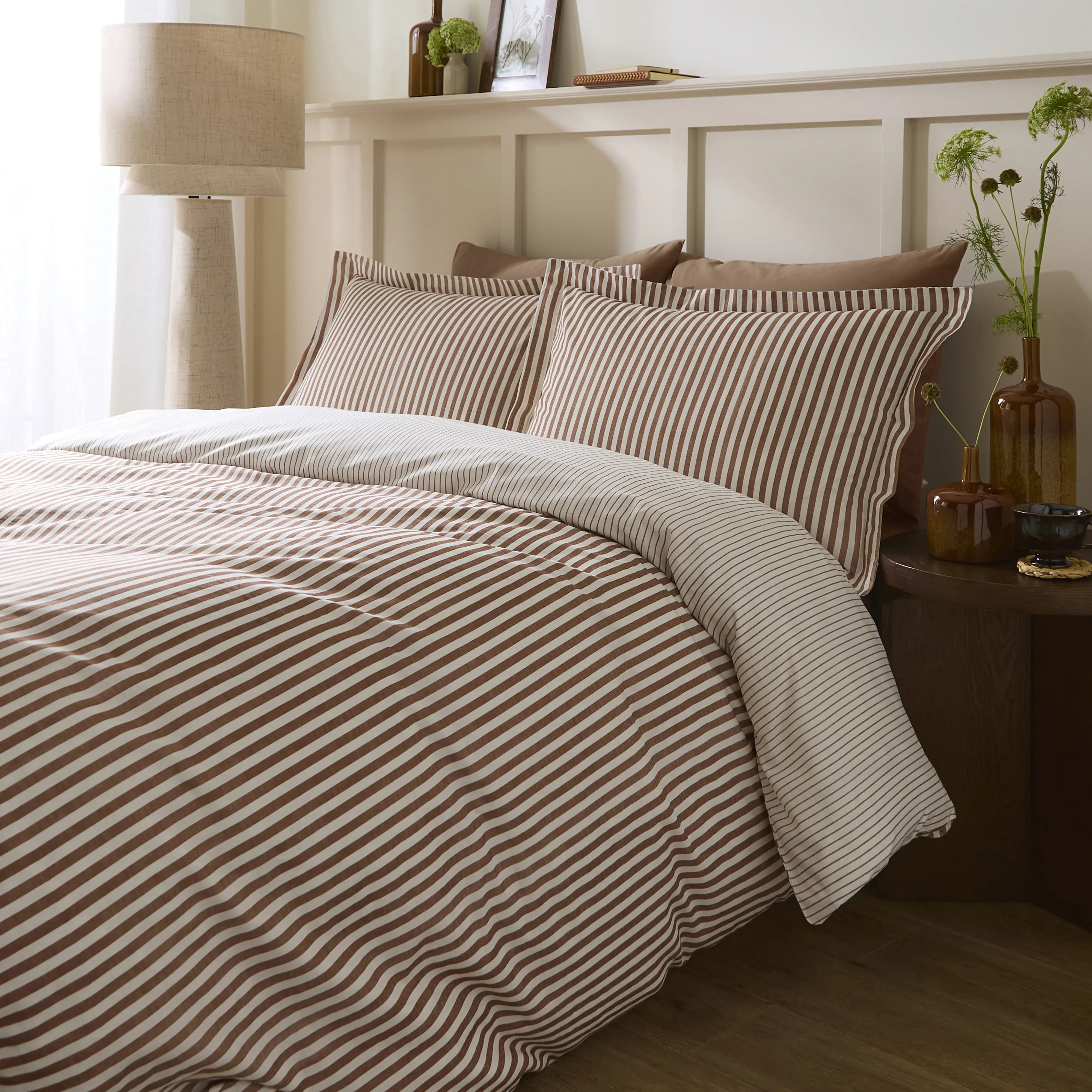brown striped duvet cover set on bed with matching pillowcases and neutral bedroom decor