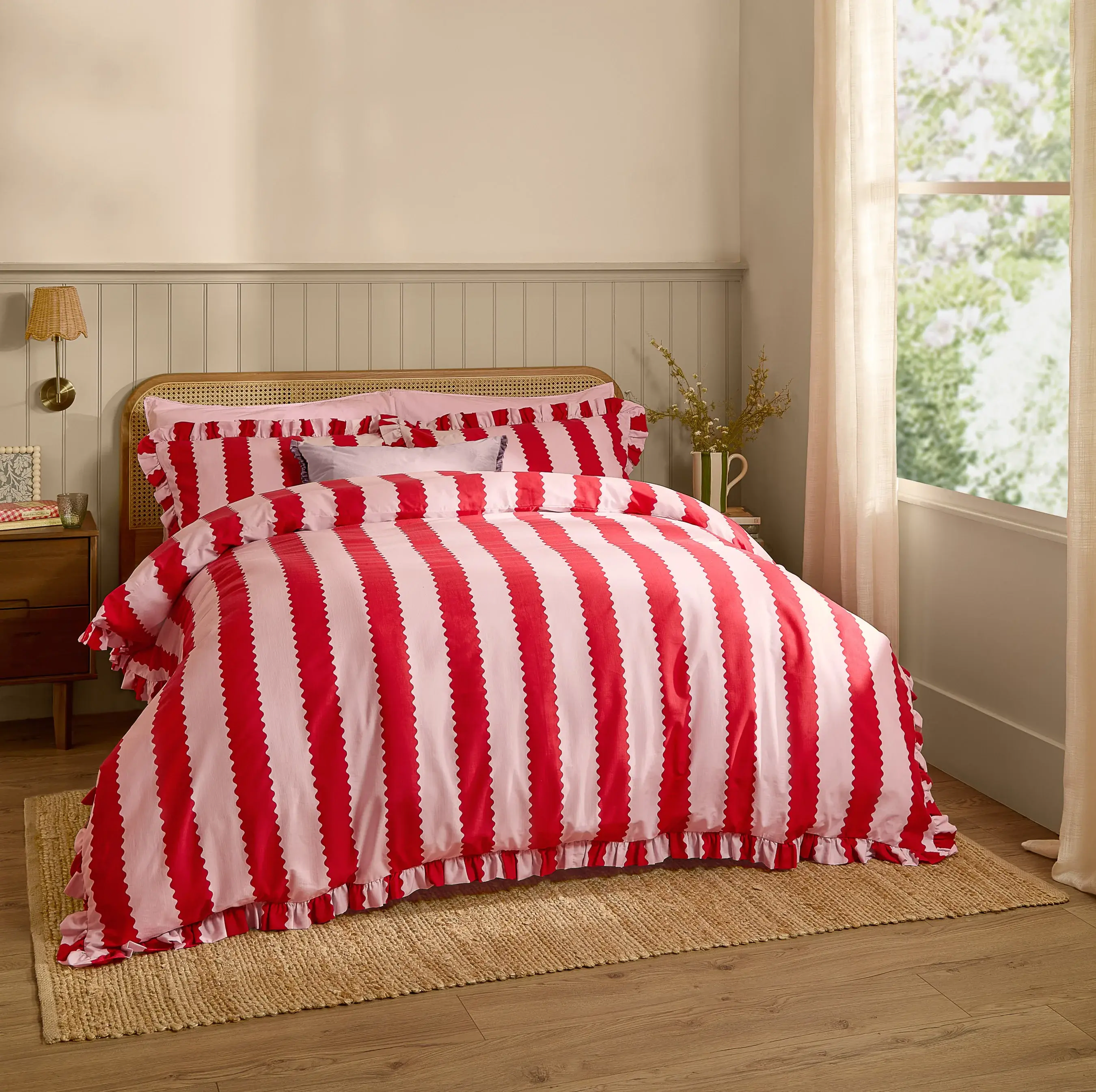 red and pink striped ruffle duvet cover set on bed with cushions and natural light
