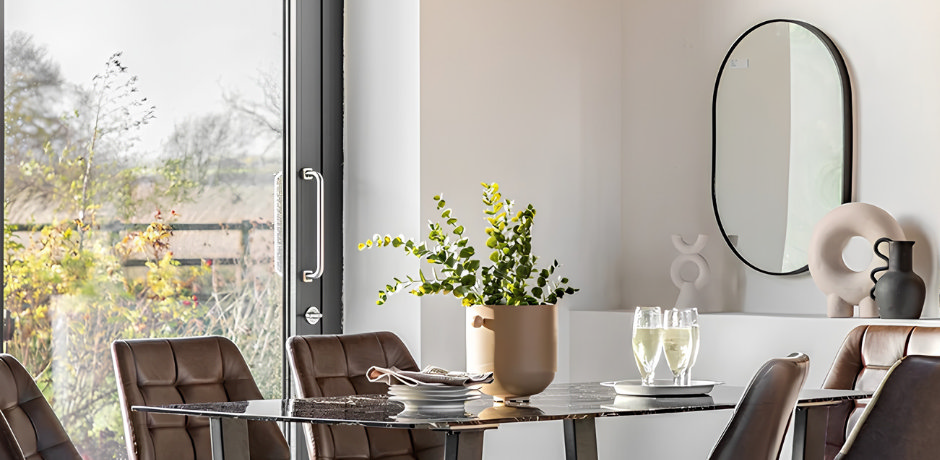 dining room with oval wall mirror above sideboard and modern dining table by window